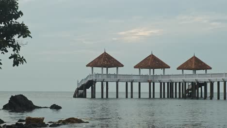 peaceful wide shot of calm sea with wooden footbridge during cloudy day in malaysia,asia