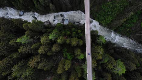 top down aerial view following a hiker walking across a suspension bridge high up above rhone river valley in valais, switzerland at goms bridge