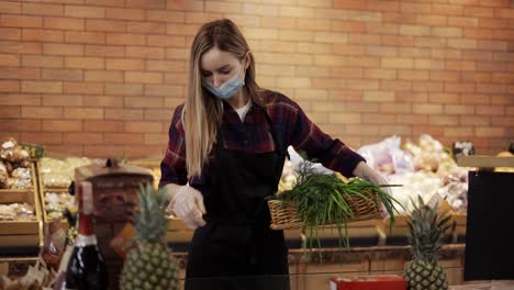 Trabajadora-Con-Delantal-Negro-Y-Máscara-Arreglando-Verduras-En-El-Supermercado,-Quitando-Cosas-Estropeadas