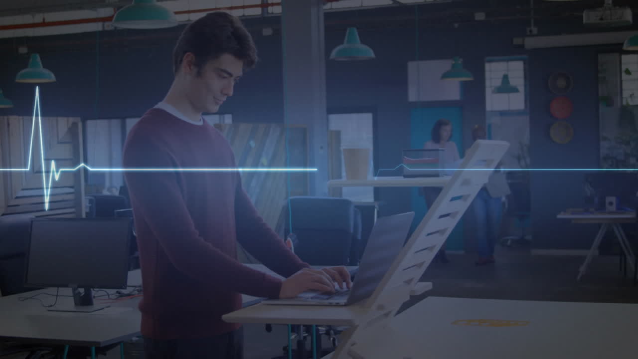 animación de un monitor de frecuencia cardíaca azul brillante, sobre un hombre que usa una computadora portátil en un escritorio de pie en la oficina