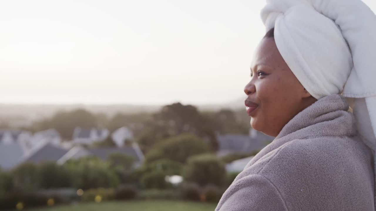 African american plus size woman drinking tea on balcony, unaltered, copy space, slow motion