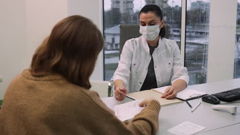 doctor writing prescription for patient