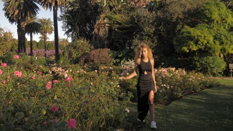 hermosa mujer caminando por un jardín de flores - en el parque centenario - sydney australia en un día soleado - toma amplia