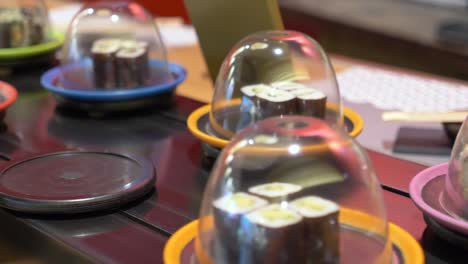 close up shot conveyor belt serving fresh sushu in a japanese restaurant in tokyo, japan