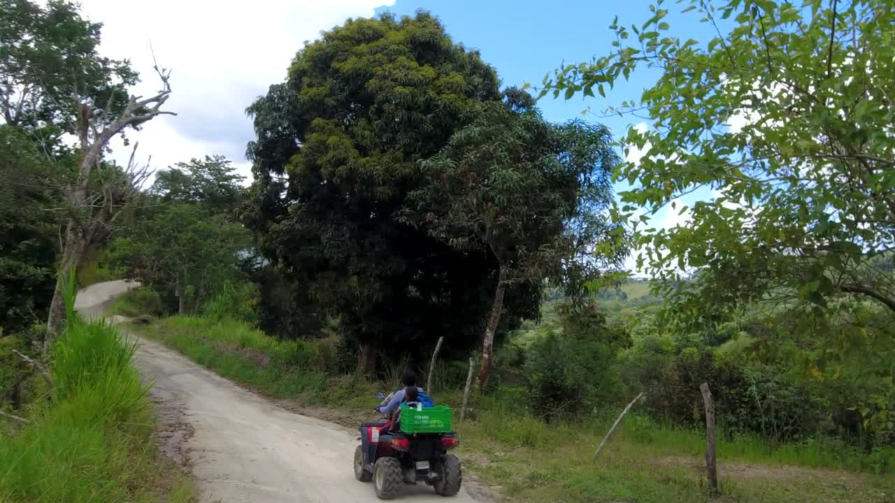 otra foto de una mujer y un niño conduciendo en una calle rural del caribe en una comunidad llamada san jose de ocoa, en la republica dominicana, el camino esta lleno de baches y el dia esta soleado