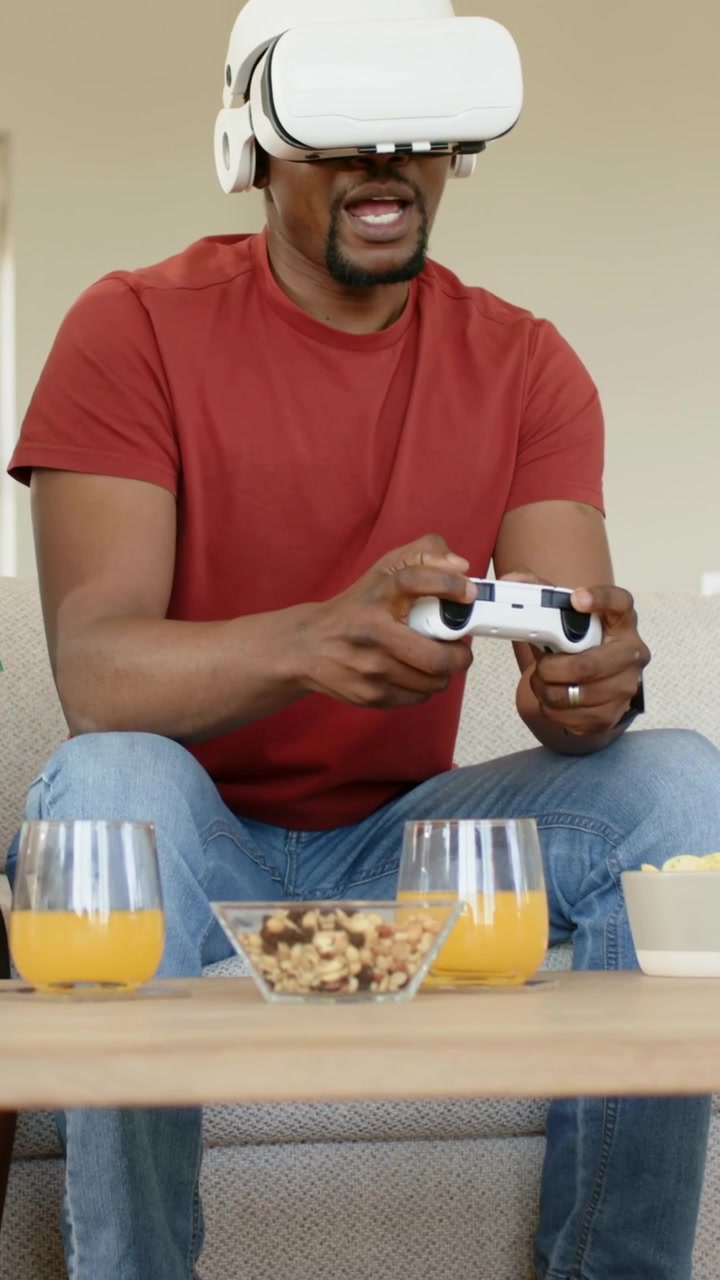 Vertical video: Reacting to VR, man in red tee with white headset using white controller at home