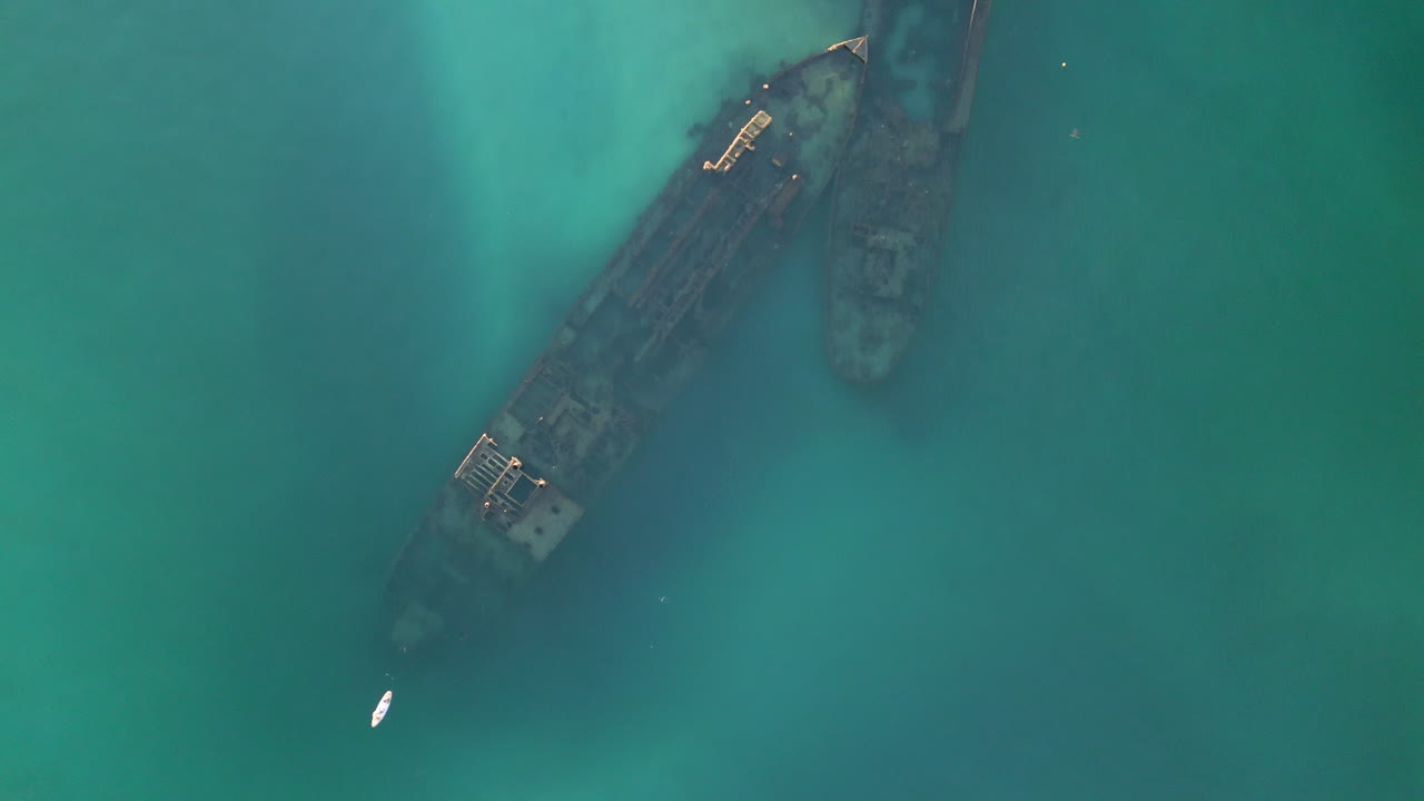 lento aéreo de arriba hacia abajo restos oxidados de naufragio, viejo barco hundido en el mar azul