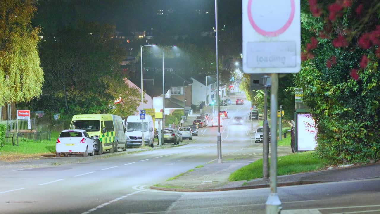 A nighttime scene showing glowing streetlights and cars passing along Queensway, a hilly road in Hemel Hempstead