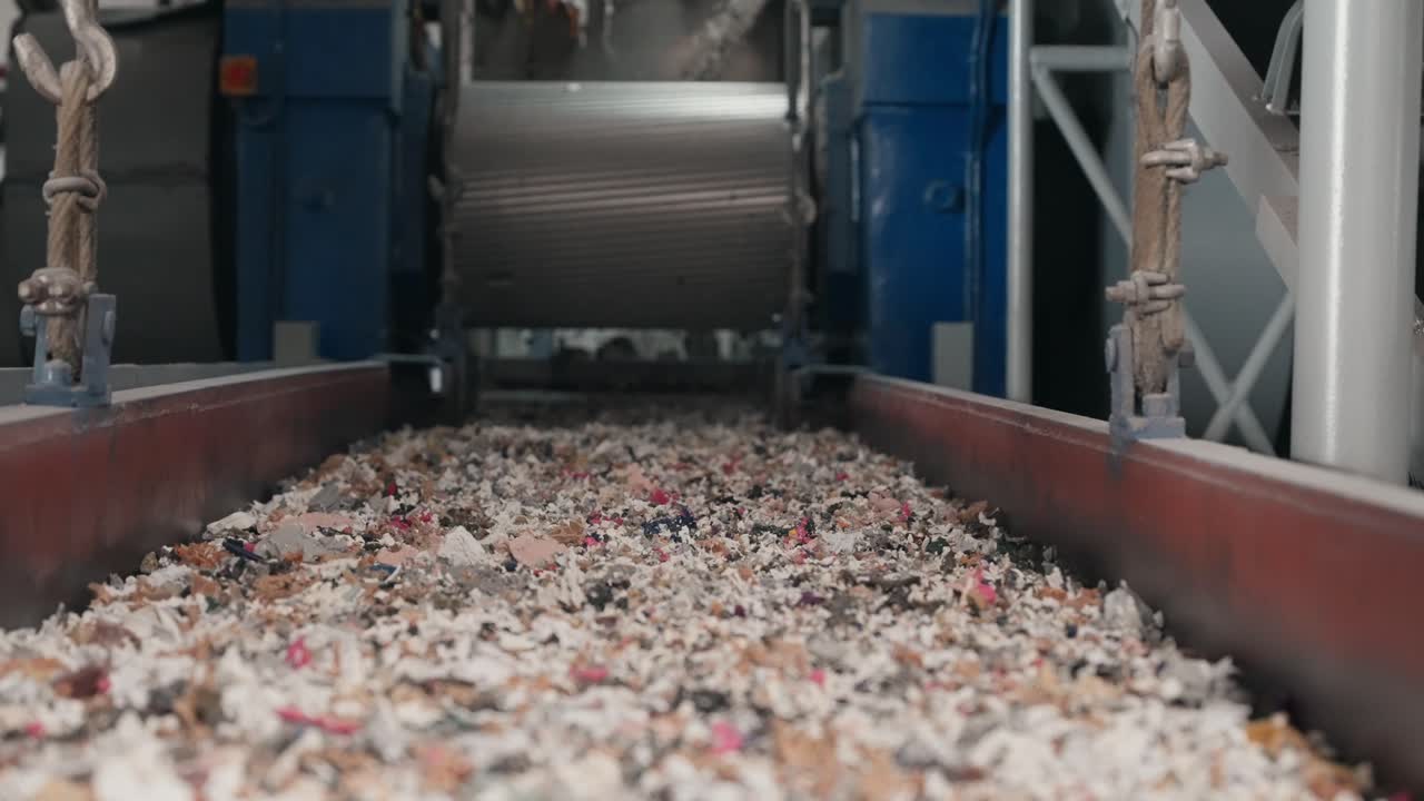낮은 산업용 컨베이어를 따라 이동하는 잘게 찢긴 폐기물 조각