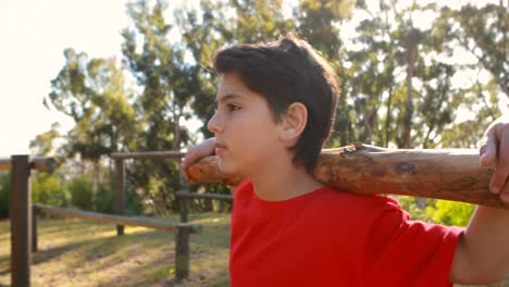 determined boy exercising with log in boot camp