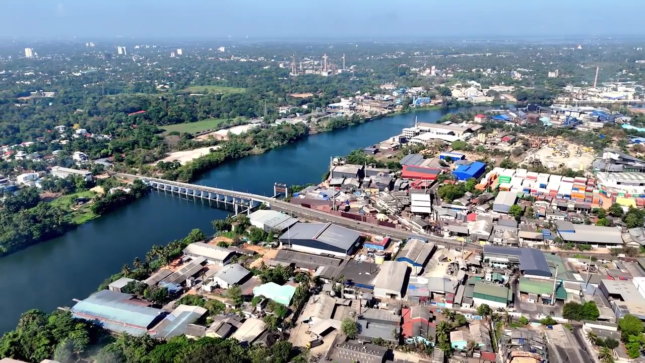 Ampia ripresa aerea cinematografica del Regolatore di Pathalam che mostra l'infrastruttura fluviale, i paesaggi industriali e i dintorni urbani tropicali che fondono lo sviluppo moderno con i corsi d'acqua naturali