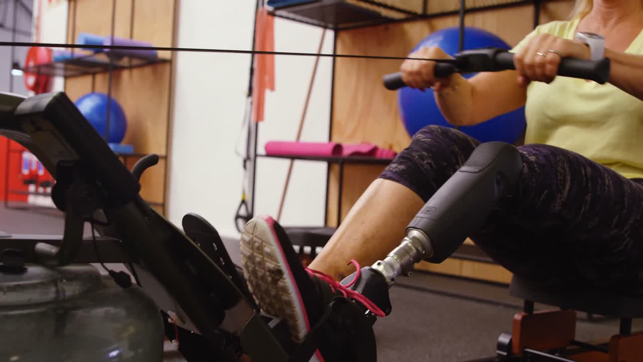 Senior woman exercising on water rowing machine 4k