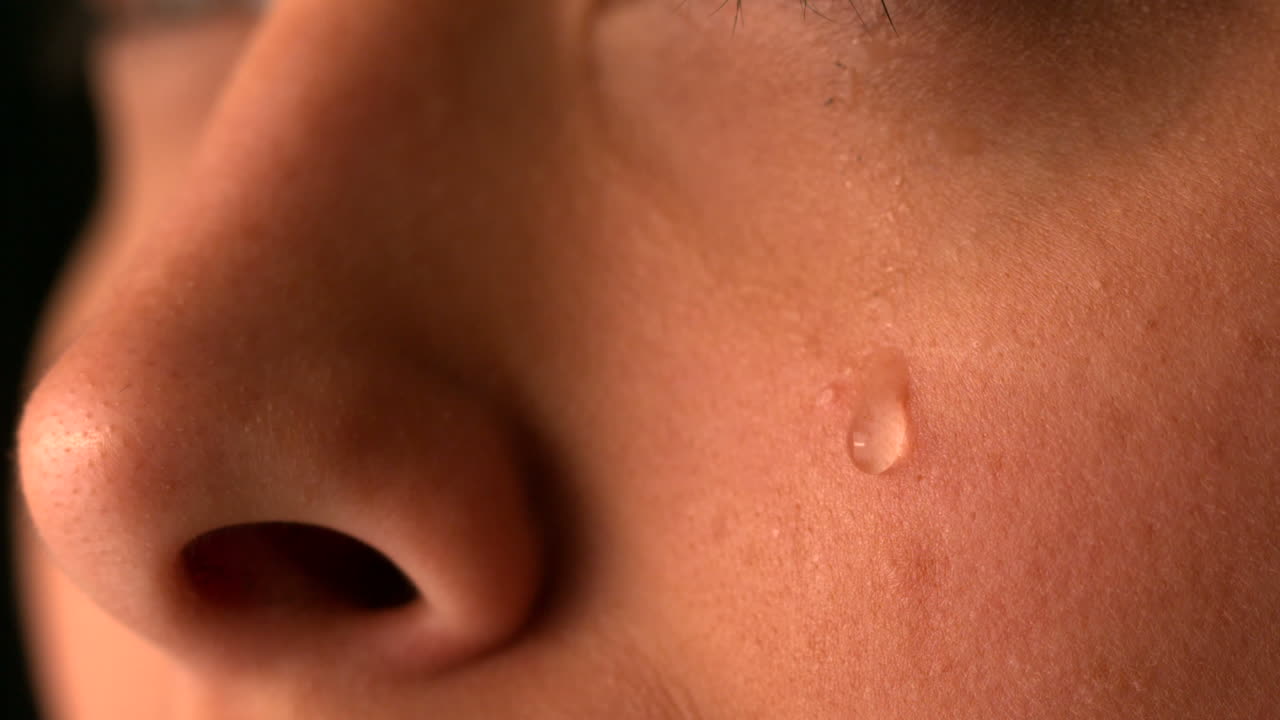 Tear rolling down womans cheek