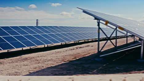 un dron captura una vista lateral de una granja solar con múltiples filas de paneles solares