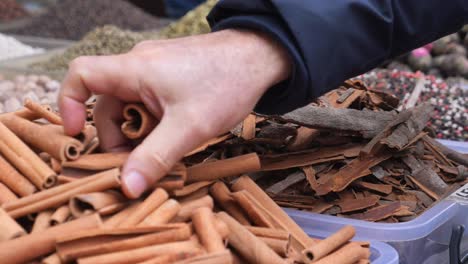 una persona recogiendo palitos de canela de una tienda de especias