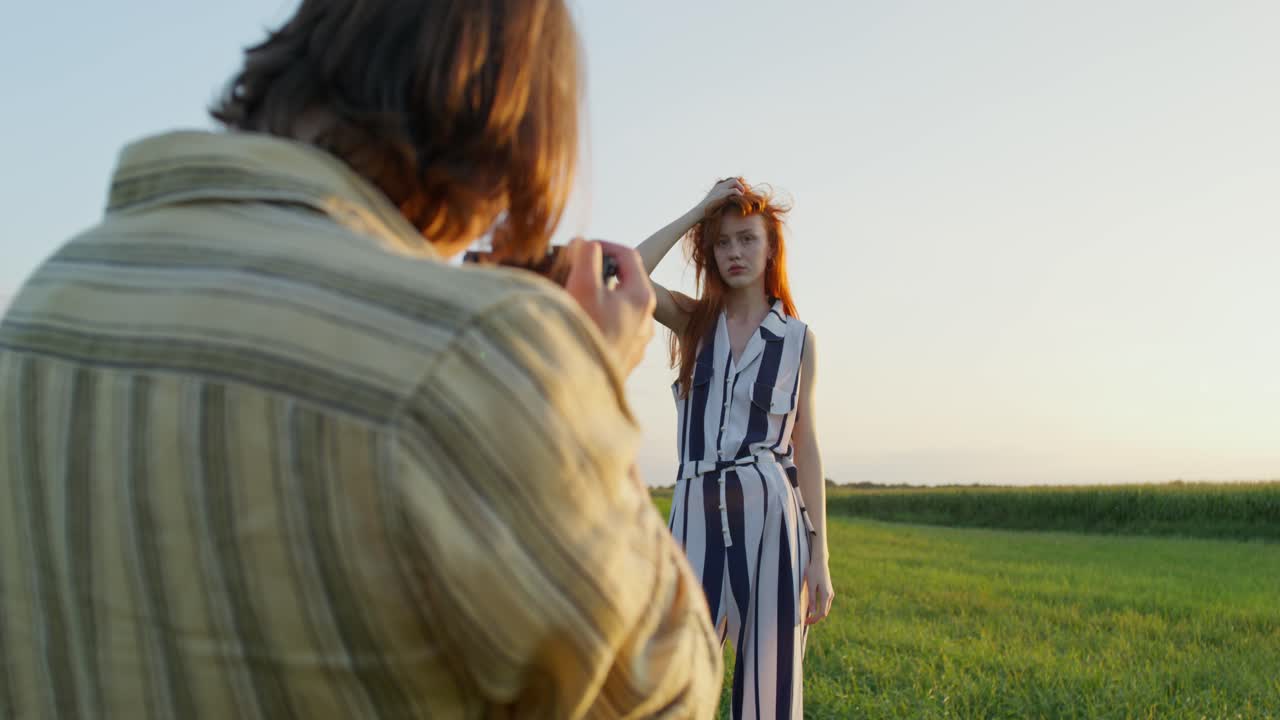 사진작가 가 해가 지는 들판 에서 모델 을 찍는다