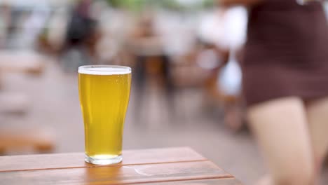 a full beer glass stands on a wooden table