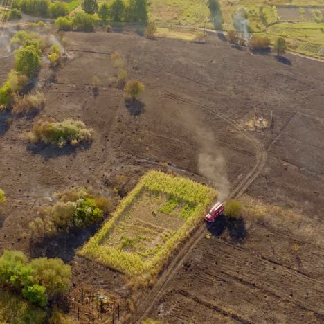 burnt field in summer. fire truck working on the field. brown field with smoke after the fire. fire disaster in nature. aerial view.