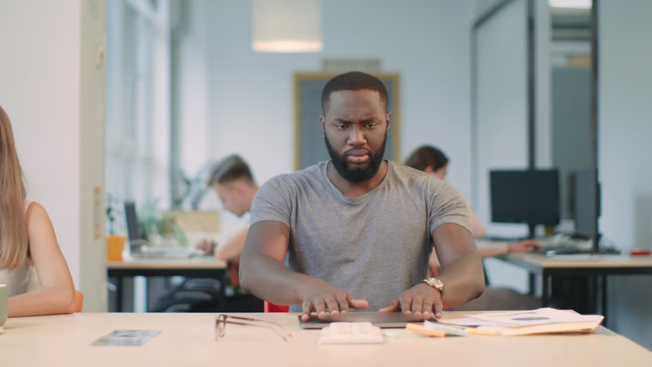 Young man getting bad news at coworking. Upset guy closing down laptop.