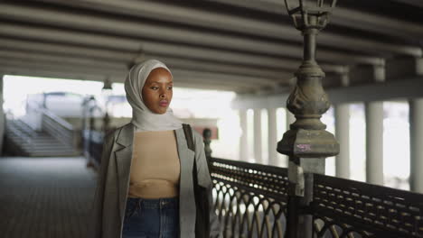 Stylish-black-woman-with-headscarf-walks-along-waterfront