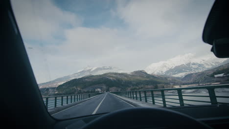 mountain panorama from front window of car driving on lake bridge road