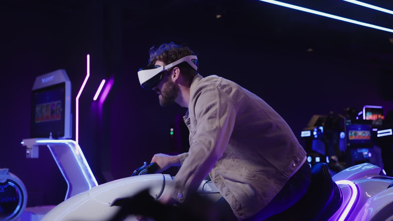 Man wearing VR headset riding a motorcycle simulator in an arcade/VR gaming center.
