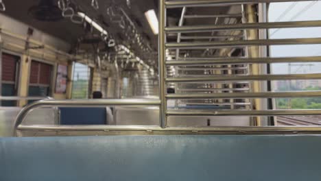 Interior-of-an-empty-train-compartment-during-travel-with-seats-and-handrails