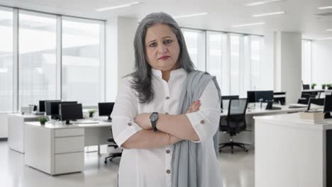 una mujer de negocios india de alto nivel de pie con las manos cruzadas.