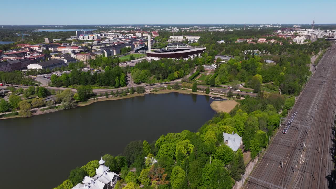 vista aérea sobre la bahía de toolo, vías de tren con el estadio olímpico de helsinki en el fondo
