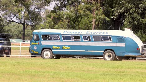 classic blue bus driving through a green field