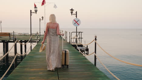 una mujer con una bolsa sobre ruedas recorre el muelle hacia el mar el sol naciente ilumina bellamente h