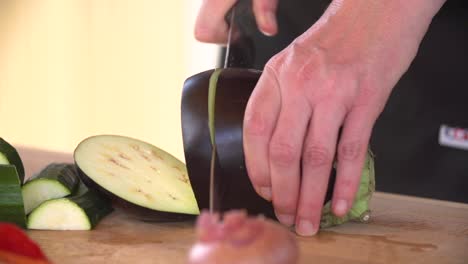 hands cut chopping a fresh eggplan on wooden board while cooking