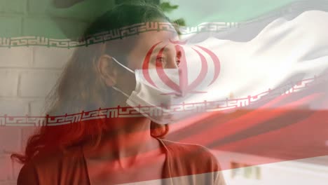 bandera iraní ondeando contra una mujer con máscara facial