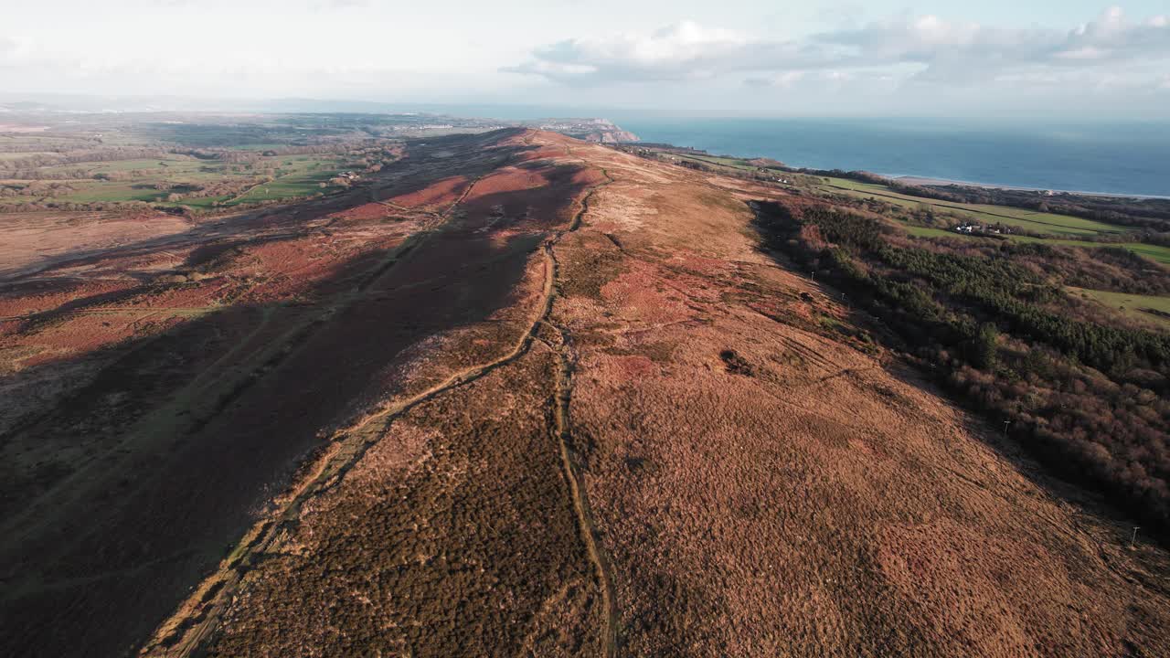 antena: panorámica lateral que muestra el sendero a lo largo de la cresta durante la puesta de sol dorada, gower, dron de 4k