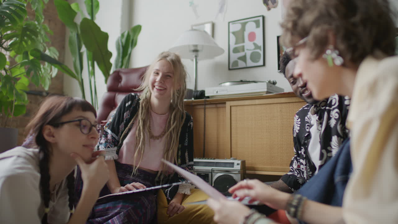 Gruppe af unge multietniske venner diskuterer vinylplader derhjemme