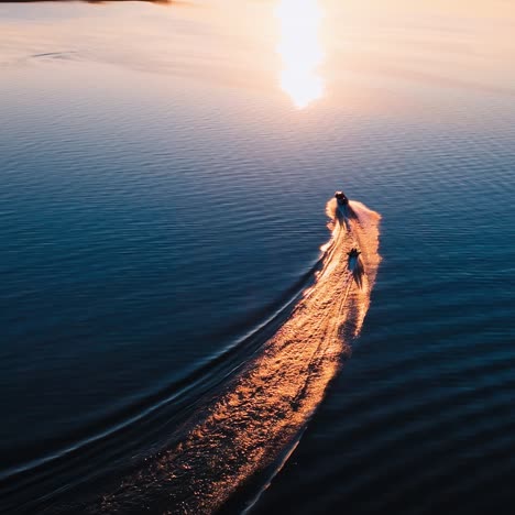 motor boat on water at sunset. panoramic view of the evening river with two boats. motor boat pulling small boat with people. view from above.
