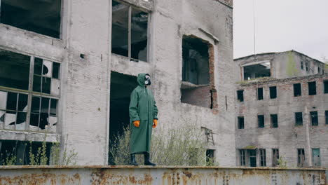 survivor in abandoned place after chemical attack. human in protective hazmat suit and gas mask standing alone in ruined city.
