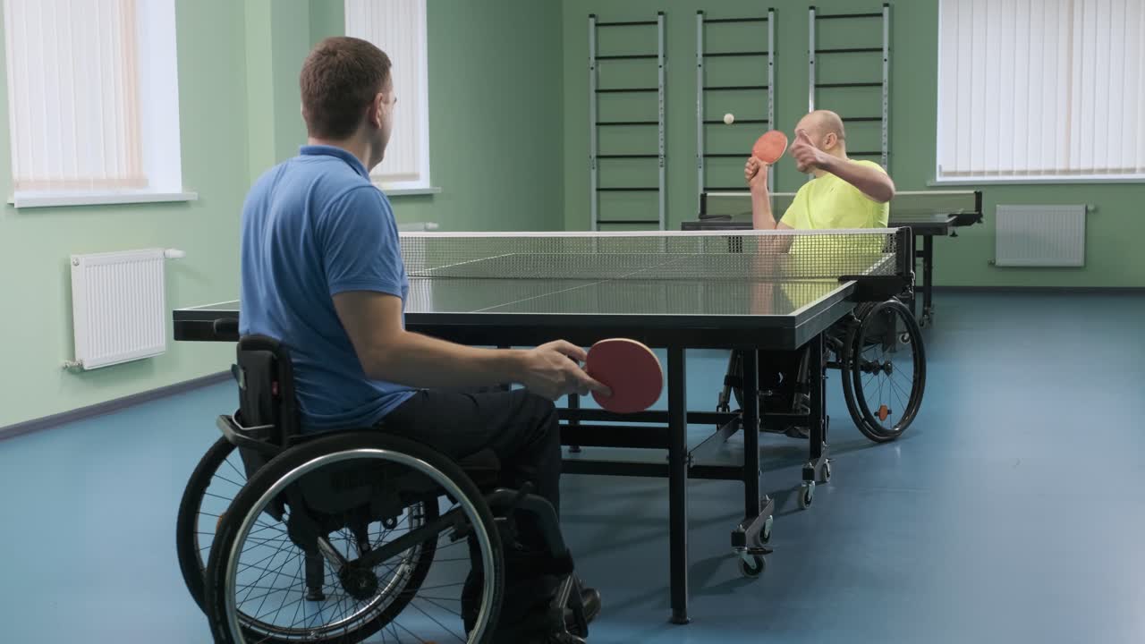 체어에 앉아 있는 남자가 핑핑을 하고, 장애인들이 탁구를 하고, 장애인의 재활, 패럴림픽 스포츠.