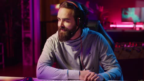fröhlicher gamer, der nicht davon betroffen ist, ein spiel mit teamkollegen zu verlieren, während er ein esports-turnier spielt