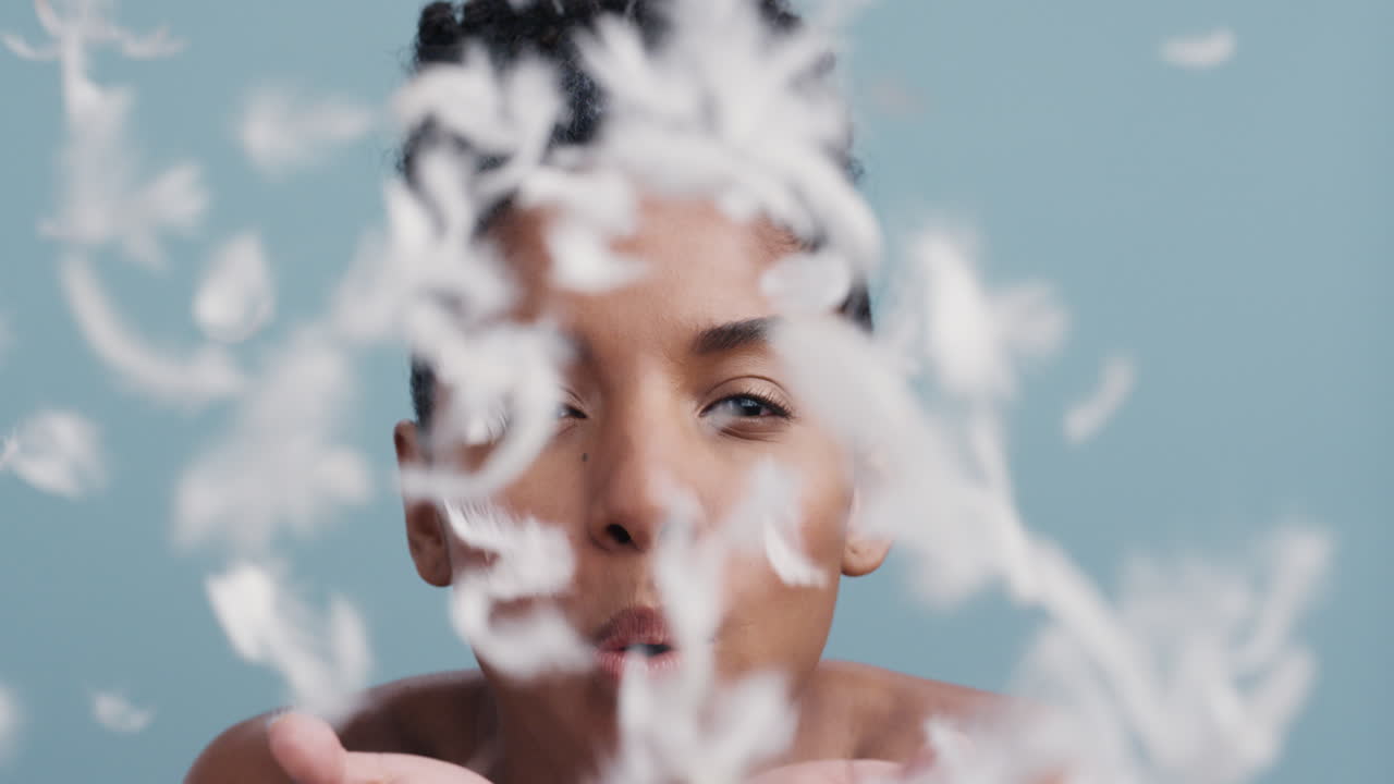 retrato de belleza en cámara lenta hermosa mujer afroamericana jugando soplando plumas cayendo tocando la piel desnuda disfrutando del cuidado suave de la piel acariciando suavemente cuerpo hermoso perfección femenina