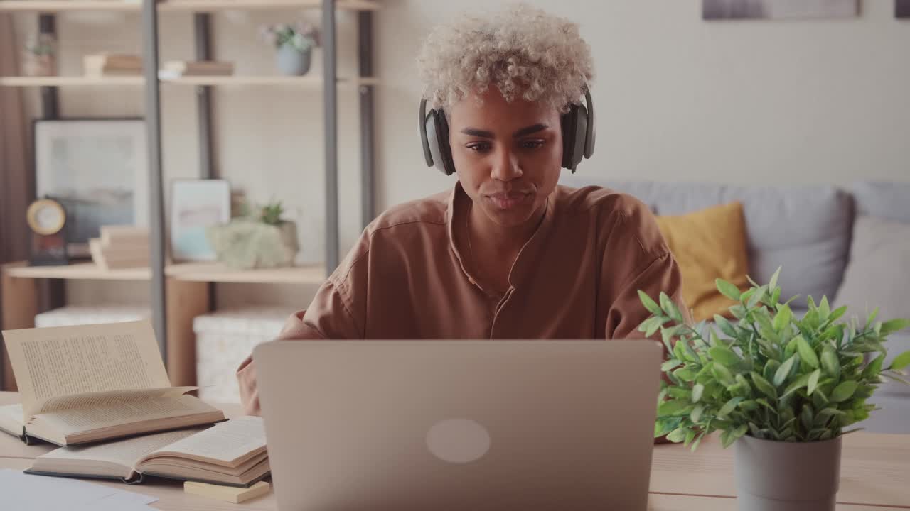 African female student wear wireless headphone study online with teacher