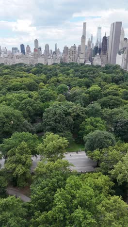 a smooth push-in vertical drone shot of central park leading into the downtown nyc skyline, showcasing the contrast between green space and towering skyscrapers