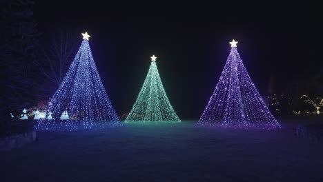 three trees created with cold lights decorations with stars on top, night