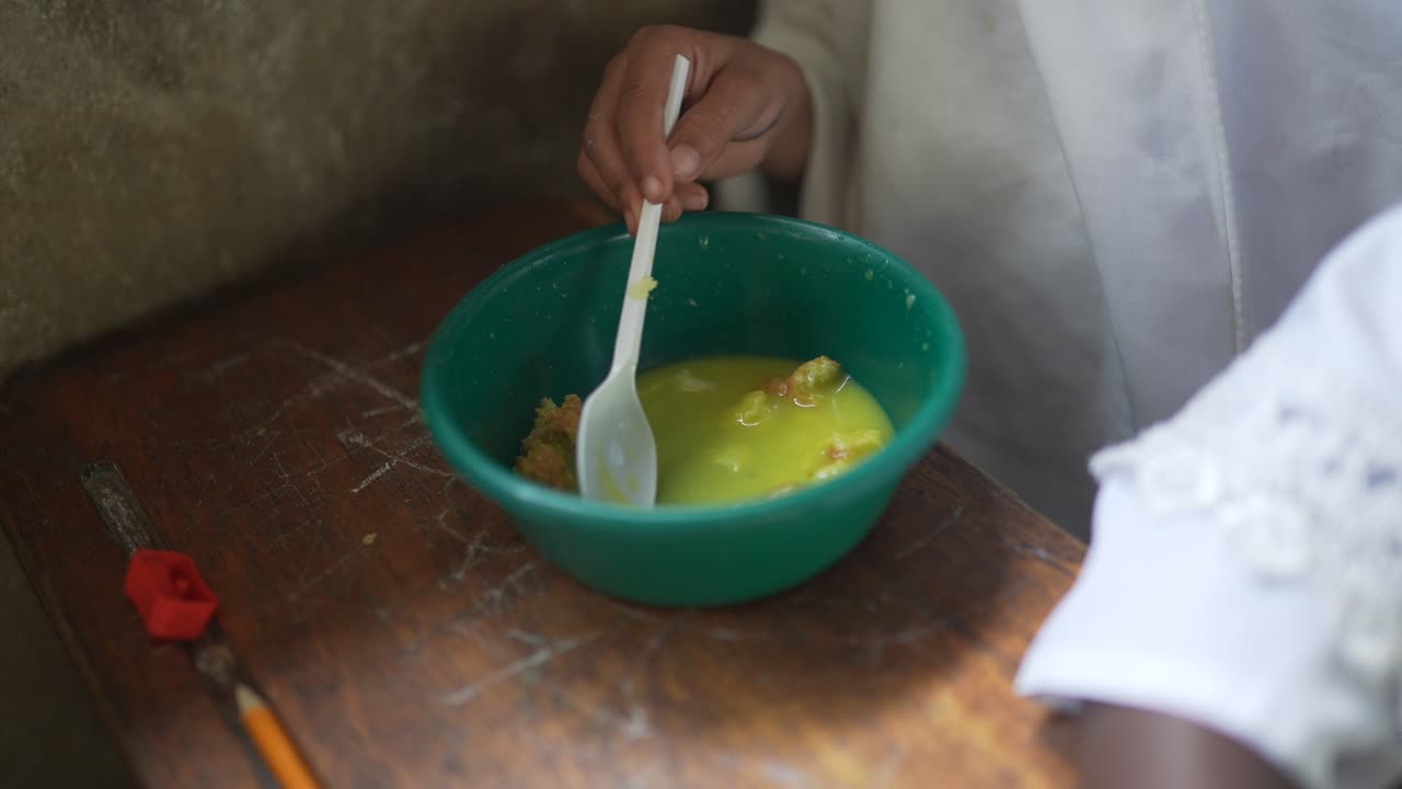 Children eating breakfast at class with a plastic spoon. Famine and hunger in Africa. Kids undernourishment, malnutrition 4K.
