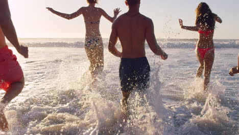 diverse group of friends swimming in the sea at sunset