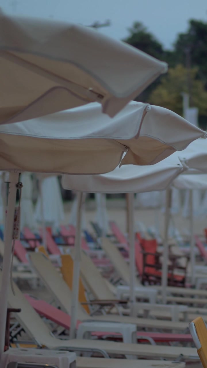 Lettini vuoti sotto gli ombrelloni in un resort in una serata ventosa
