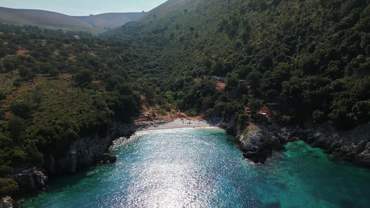 Aerial drone view of a hidden bay on the Albanian Riviera with turquoise water, cliffs, and green hills. Peaceful summer coastal landscape ideal for travel and nature projects