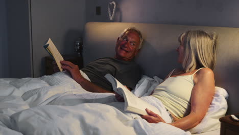 senior couple wearing pajamas lying in bed reading and talking