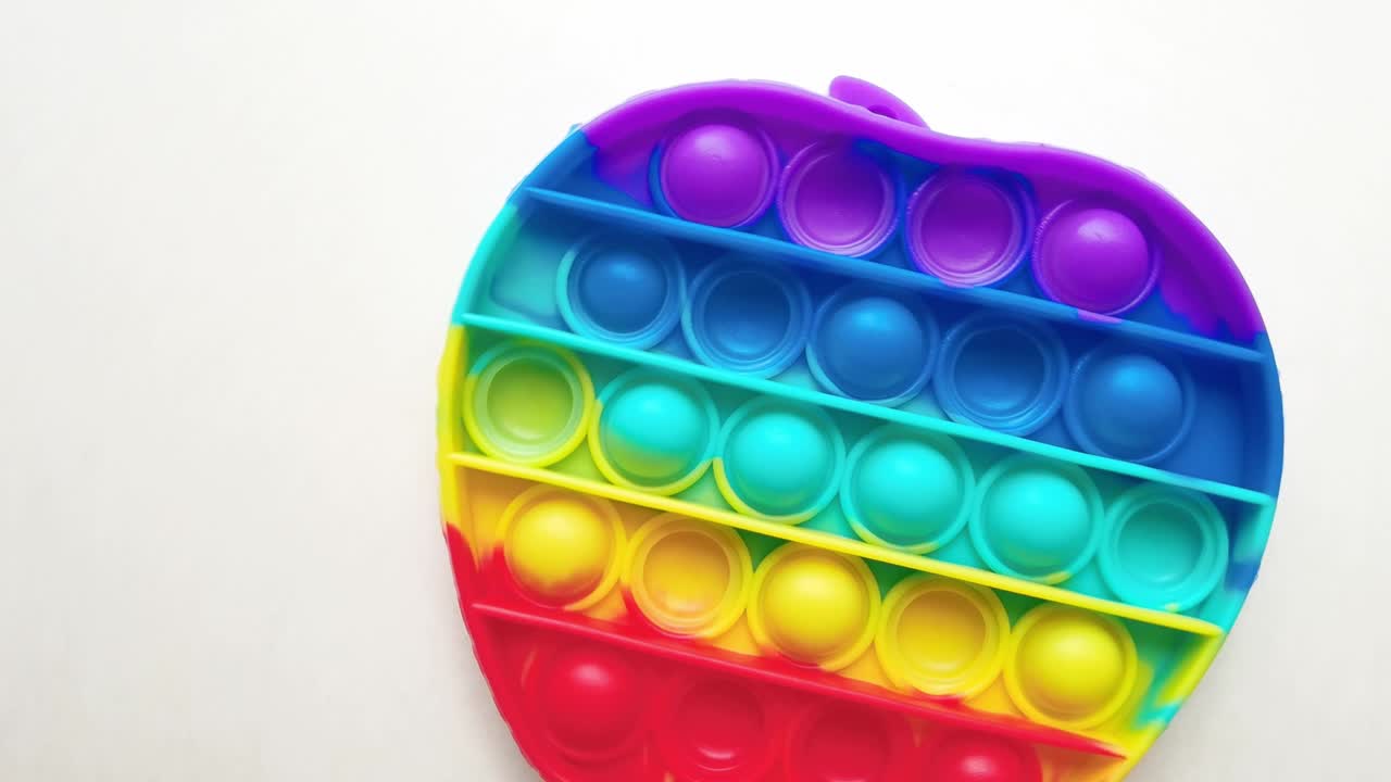 nuevo juguete para bebés. pop it juego de dedos. color gracioso. colorido juego girar en la mesa blanca. forma de manzana arco iris