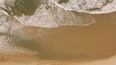 ocean waves gently crushing into an yellow sand beach, drone moving to the right